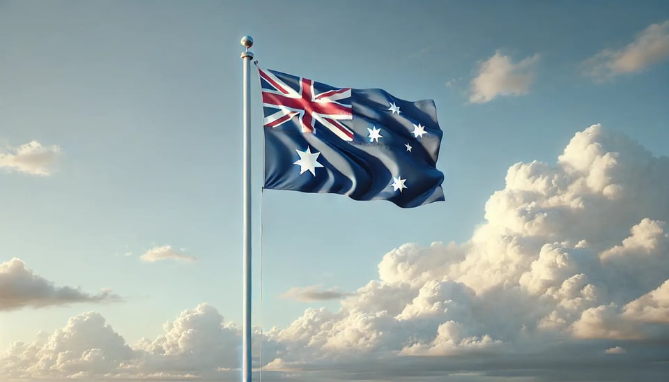 DALL·E 2025-04-15 10.57.00 - A realistic, professional landscape photo of the Australian flag gently waving on a tall white flagpole, under a clear blue sky with minimal soft clou