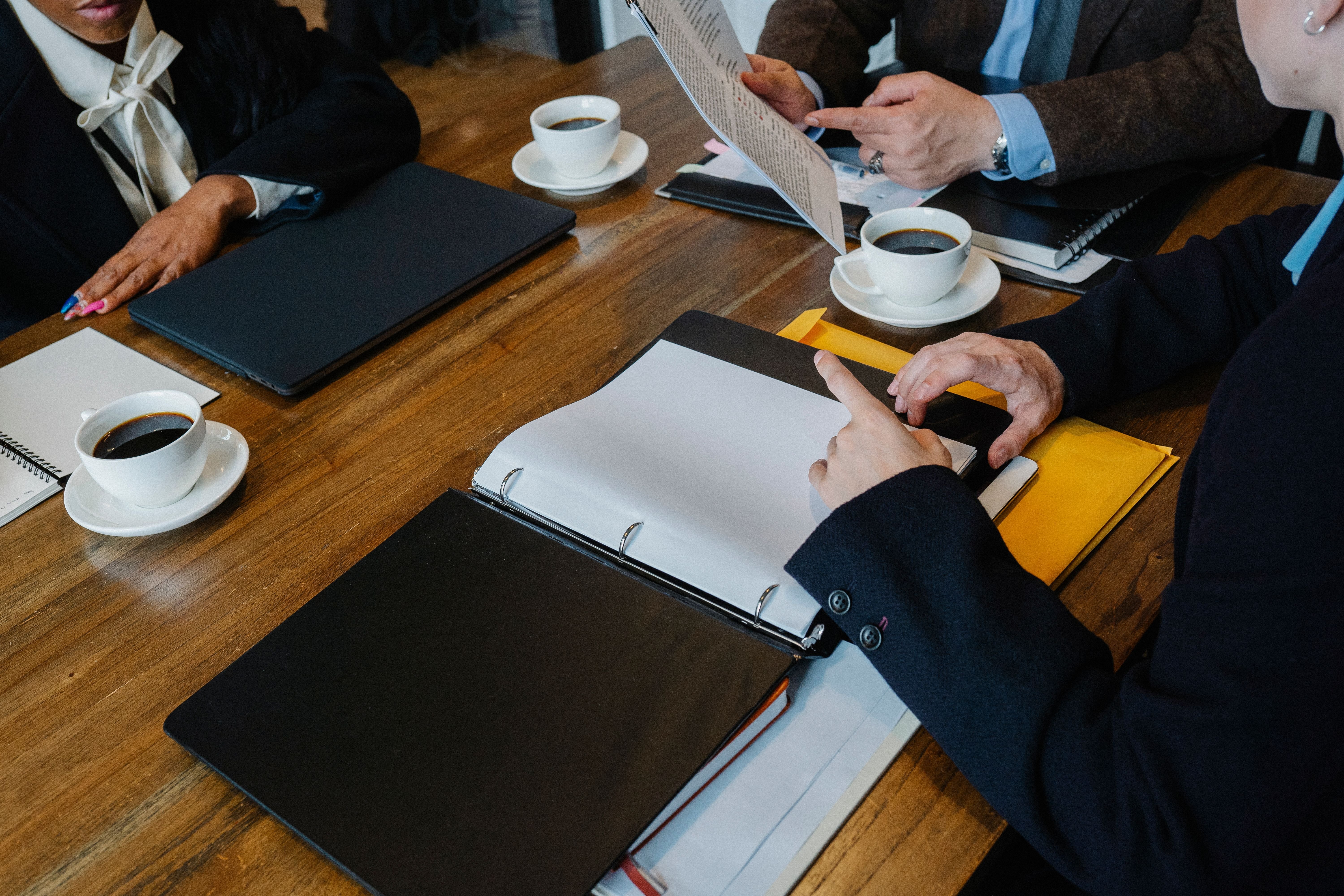 Diverse business team reviewing documents at a table to track CPD points and records.