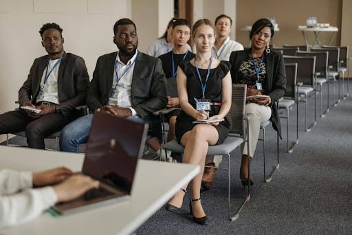 Barristers attend a legal CPD seminar, listening to a presenter and taking notes.